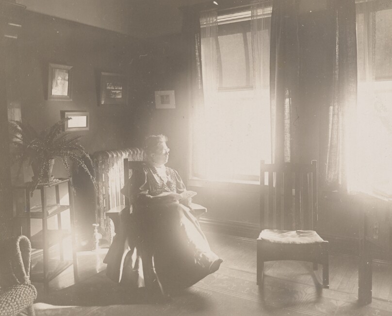 [Elderly woman seated in rocking chair, indoors]