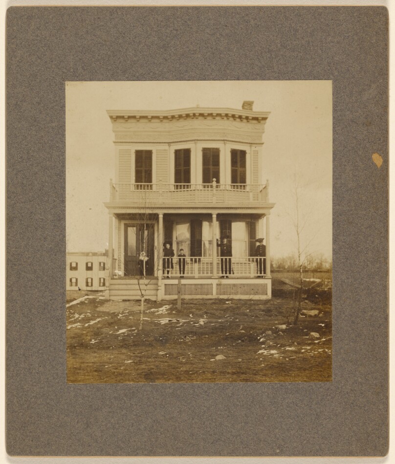 [View of a Victorian-style house with five people on the front porch]