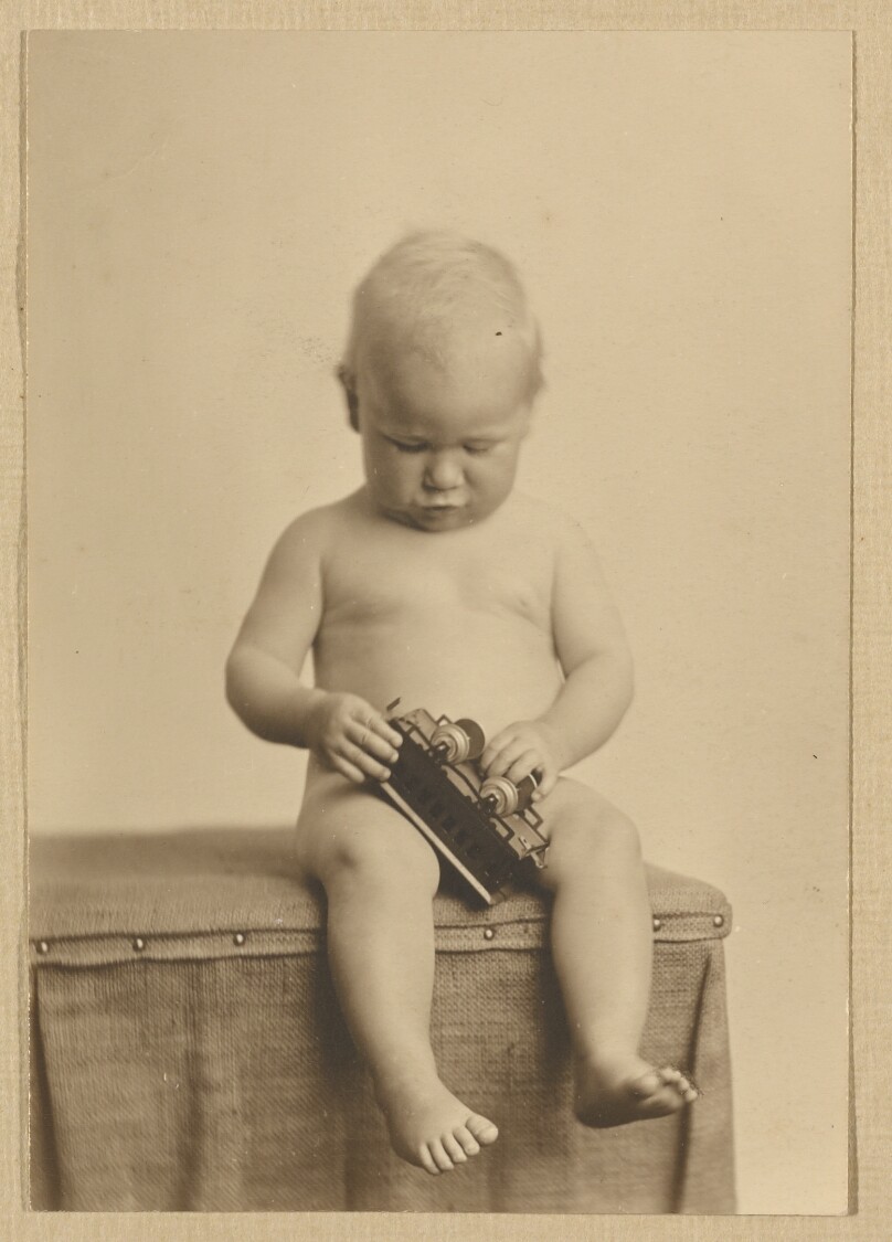 [Chandler Weston nude, seated, holding a toy train]