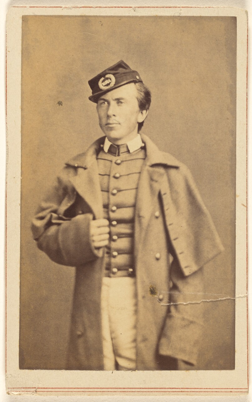 [Unidentified Civil War soldier standing, one hand grasping his overcoat]