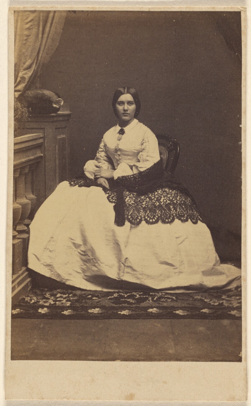 [Unidentified woman in a white dress with dark shawl, seated]