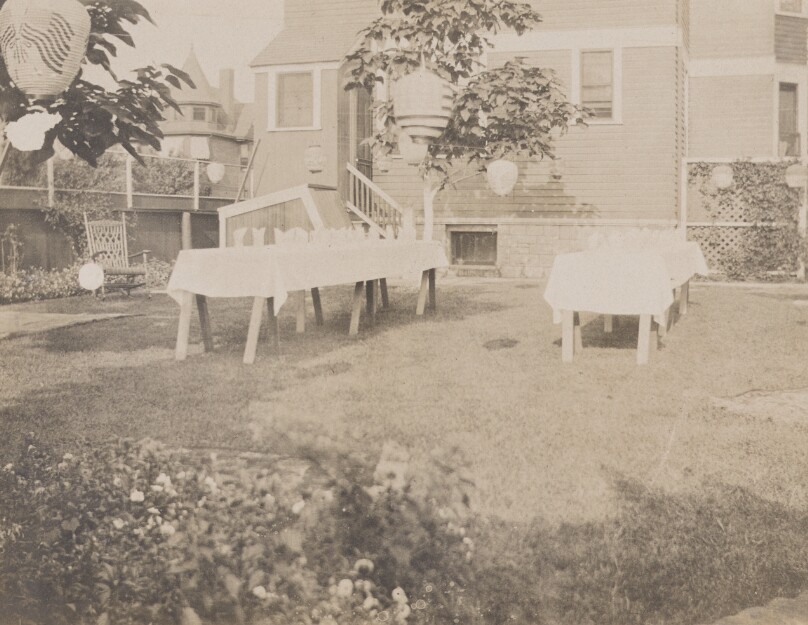 [Backyard decorated for dinner party with paper lanterns and table settings]