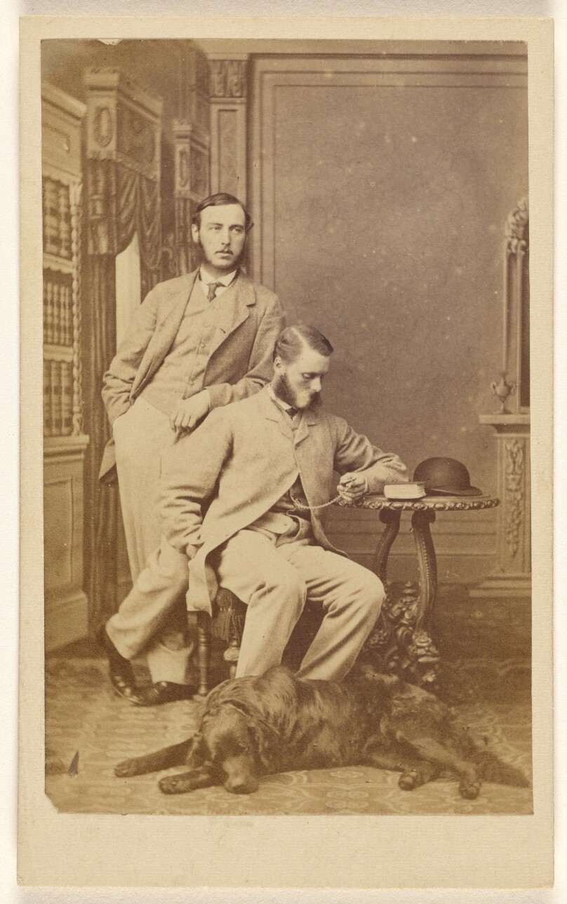 [Two unidentified men with muttonchops: one standing, one seated looking at a pocket watch, a dog is at their feet]