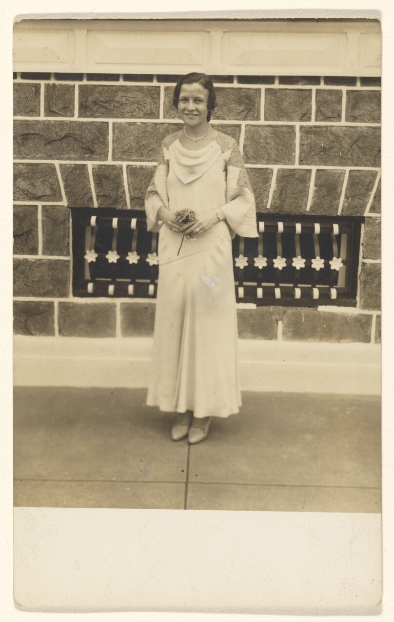 [Woman standing holding a bouquet]