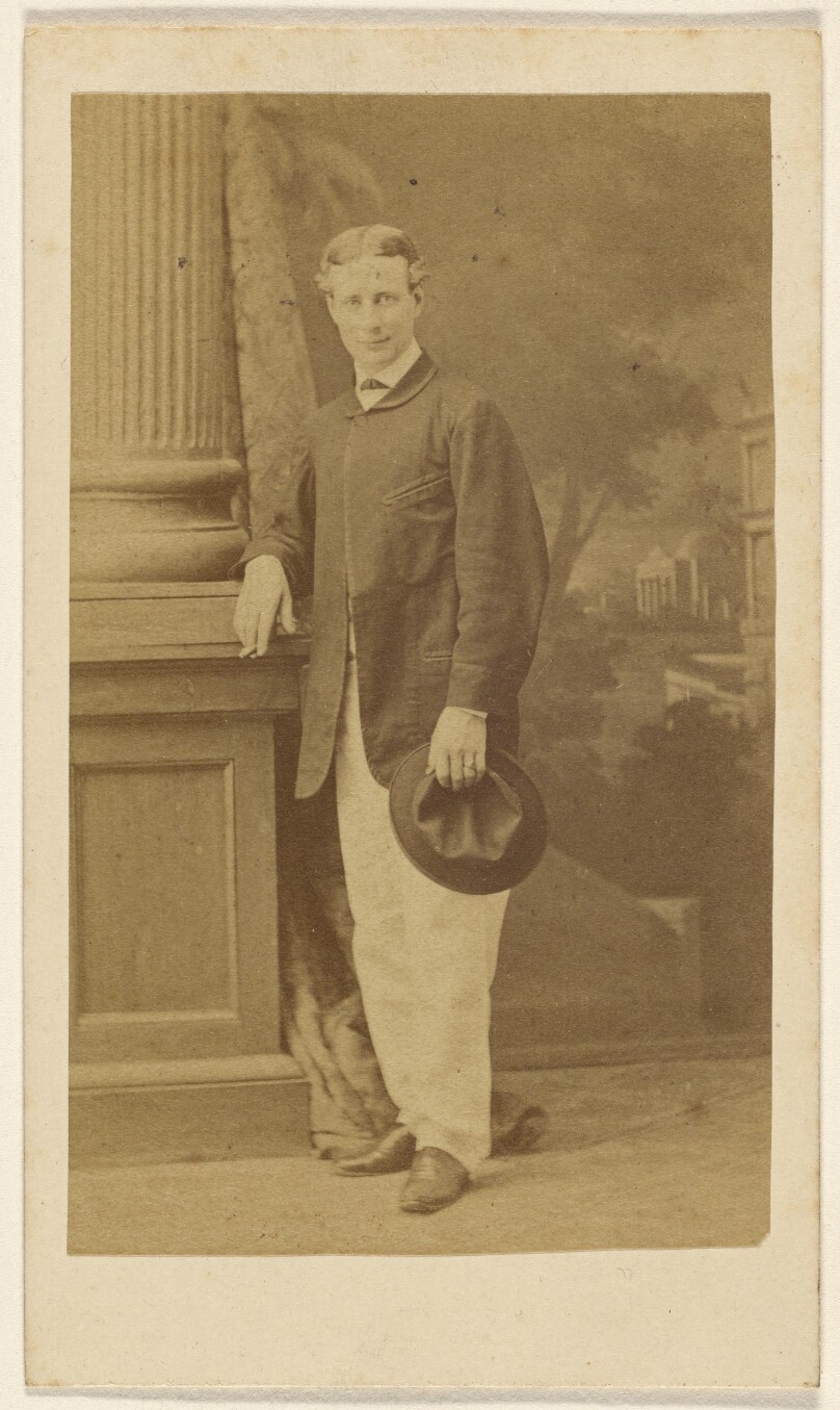 [Unidentified young man standing with cigar in one hand, his hat in the other]