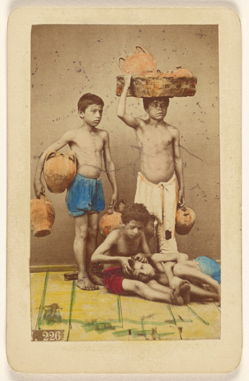 [Four unidentified boys: two standing with clay pots, two seated with one being checked by the other for head lice]