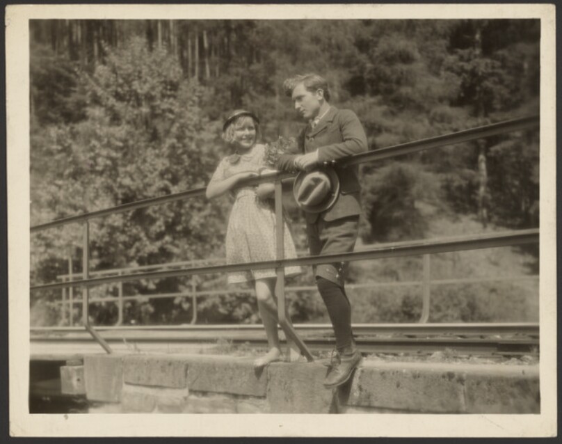 [Film still of boy and girl on bridge]