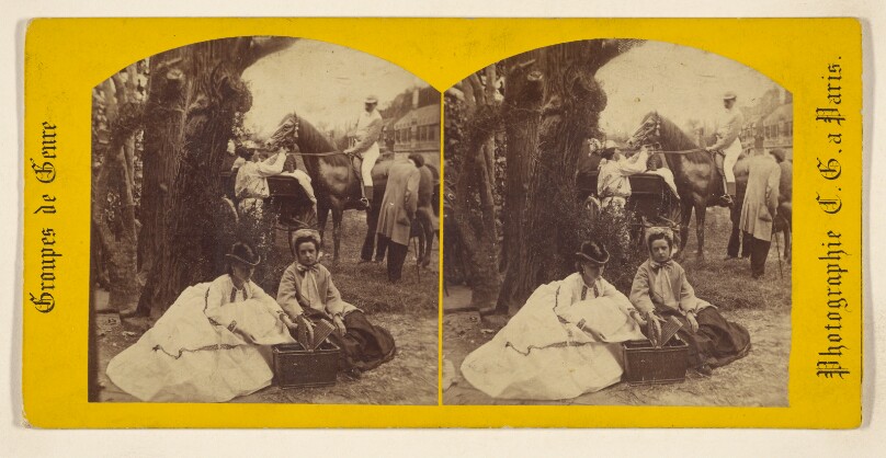 [Two women seated on the ground with a picnic basket, several men in the background, one on horseback]