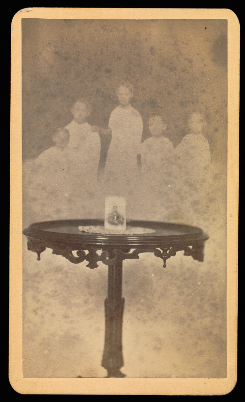 [Five "spirits" in background with a photograph at center of table with a doily]