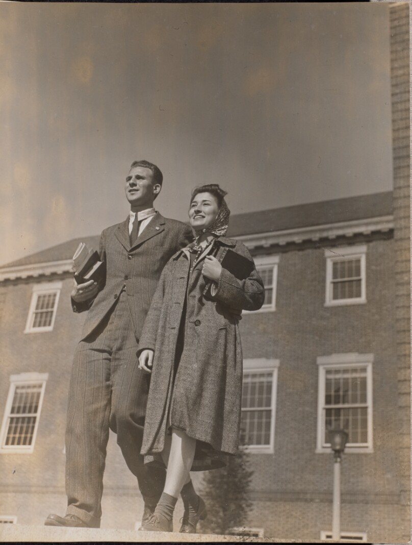 [A smiling man and woman walk towards the camera]