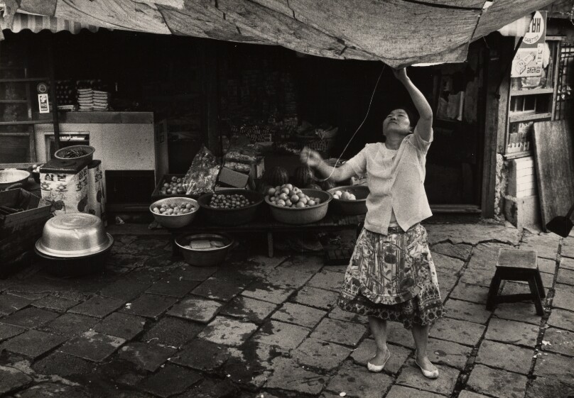 Woman Fixing Awning at Market