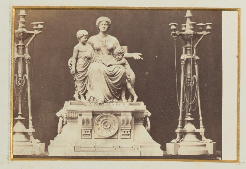[Sculpture of a mother with two children, clock at base between two large candelabras]