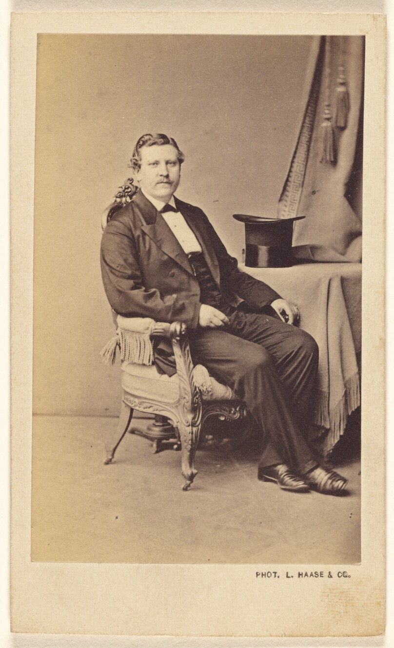 [Unidentified man with moustache seated, a top hat on a nearby table]