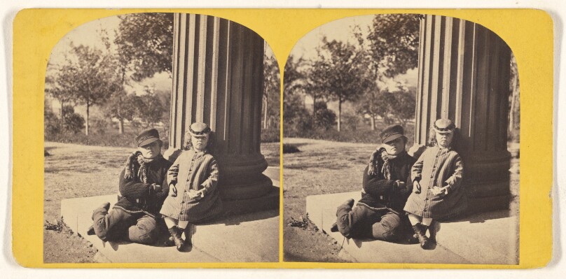 [Two children posed outside near a column]