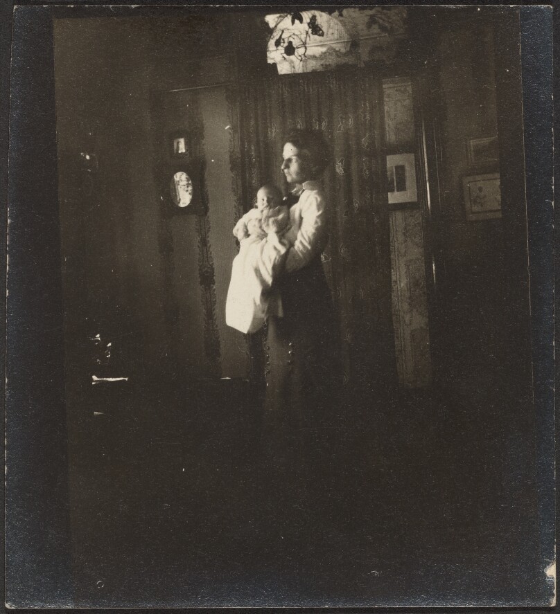 [Woman standing and holding baby]