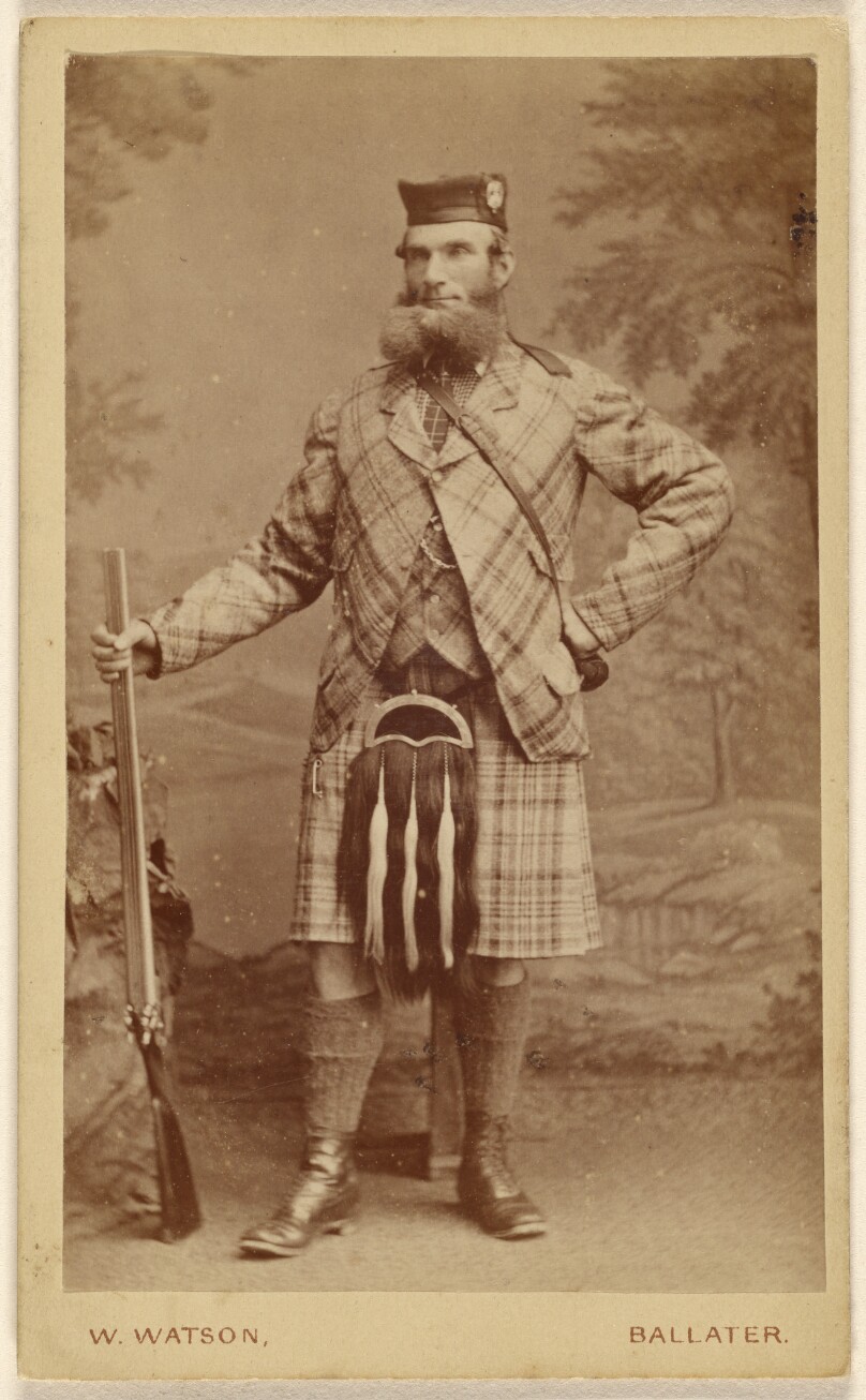 [Unidentified bearded Scottish man wearing a kilt, holding a rifle, standing]
