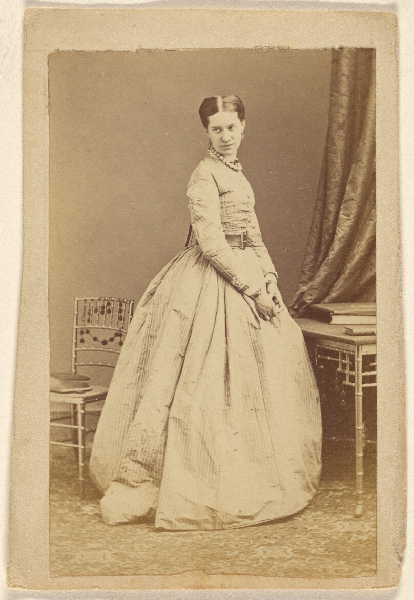 [Unidentified woman wearing a long dress, standing]