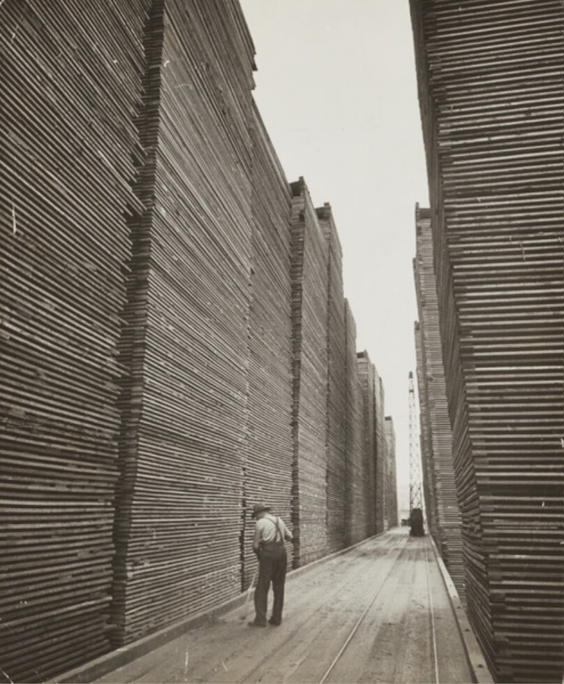 Man Sweeping Lumberyard: Seattle Cedar Lumber Manufacturing.