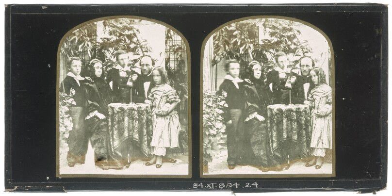 [Unidentified family group: mother and father seated at a table, two boys and a girl standing with them]