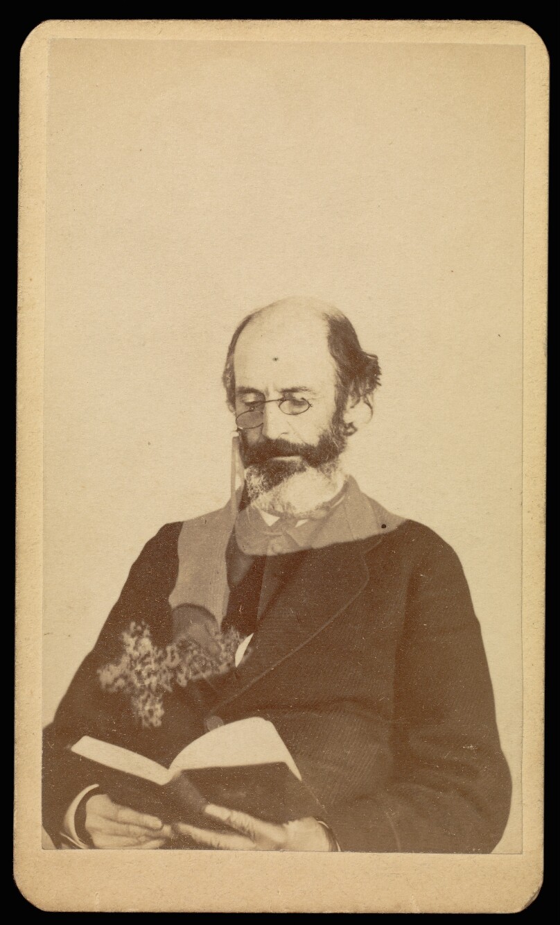 [Unidentified balding, bearded man reading while seated]