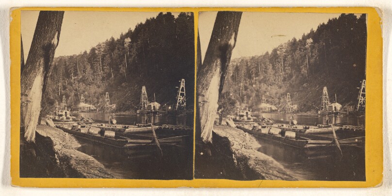 [Large rafts on river loaded with barrels, derricks on shore]