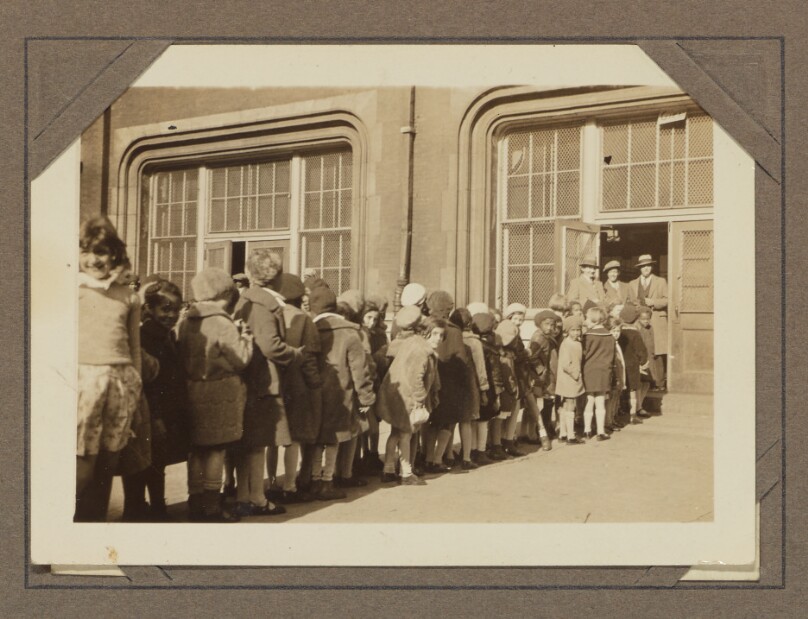 [Students line up outside of a building]