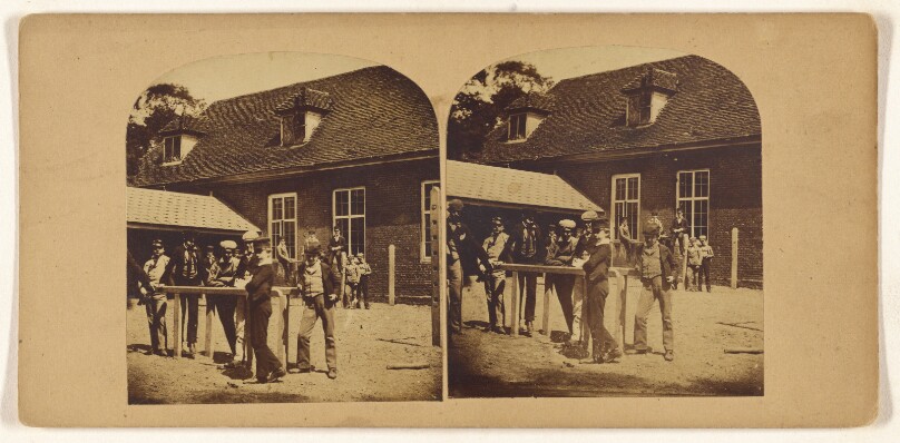 [Group of boys posed at a table outside, large house in background]