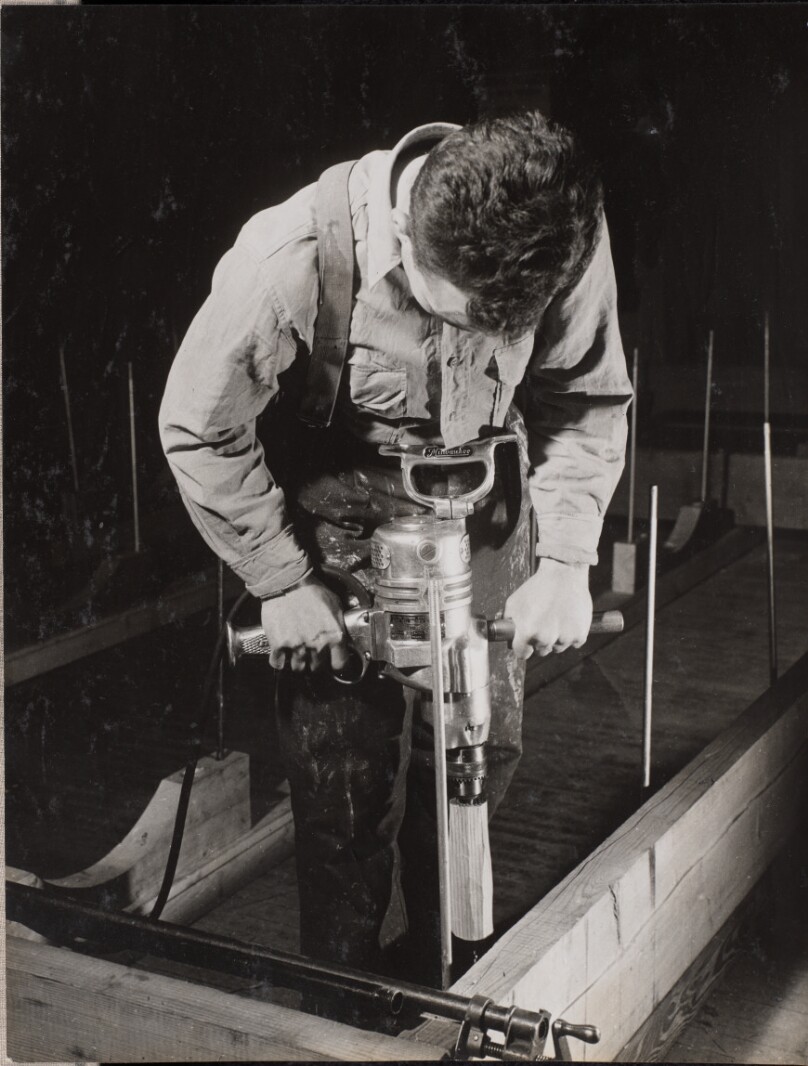 [Man uses a handheld machine to work with a piece of wood]