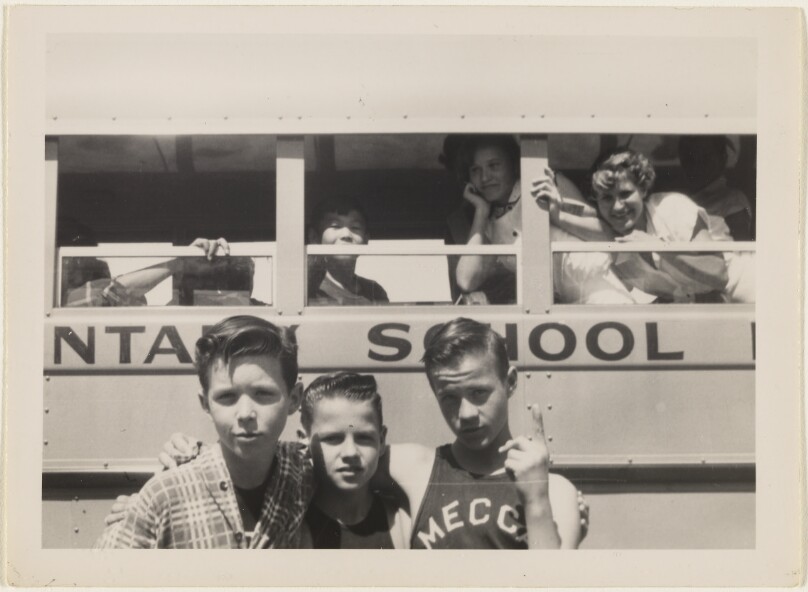 [Three boys in front of school bus]