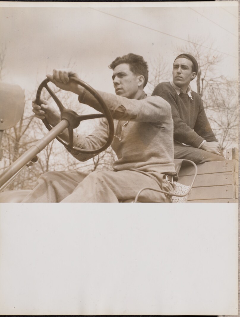 [Two men driving a truck]