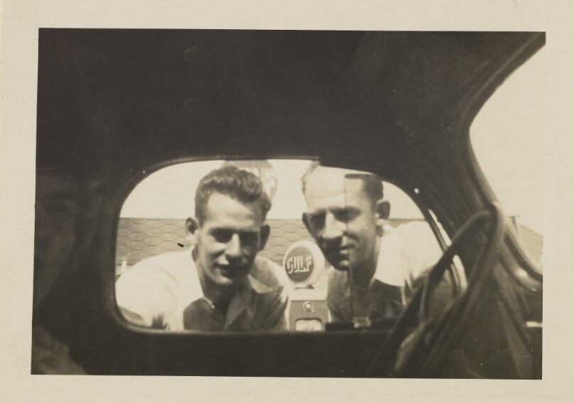 [Two men looking in car window]