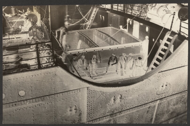 [Negative print of ship deck with workers seated]