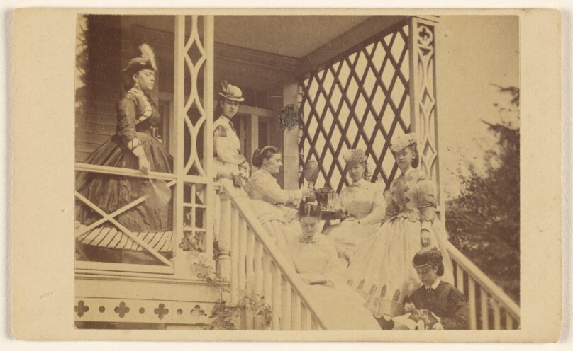 [Seven women either seated or standing on a porch or stairs]