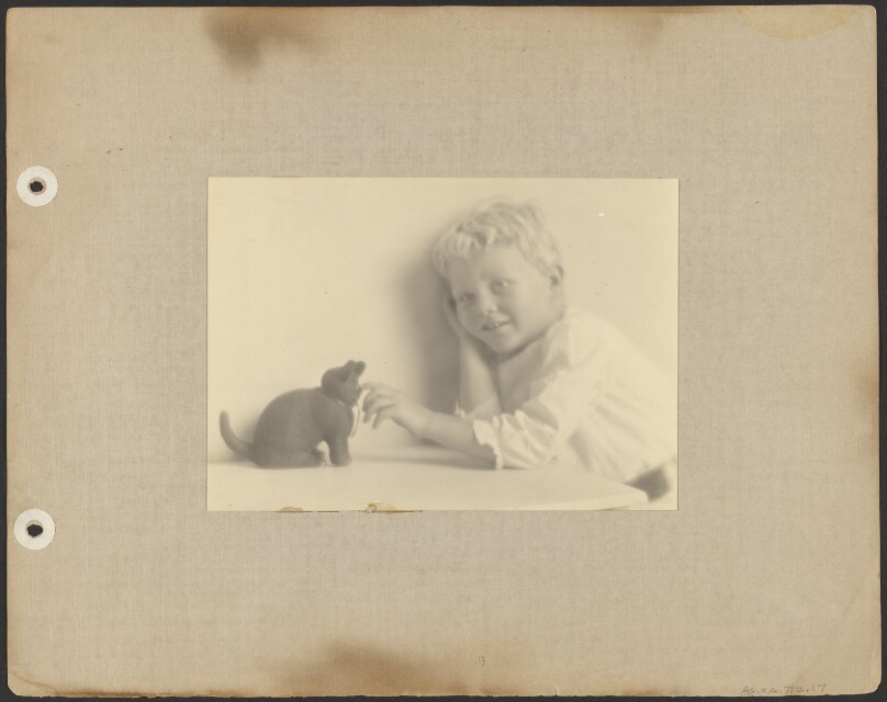 [Brett Weston in white tunic, playing with black rubber cat]