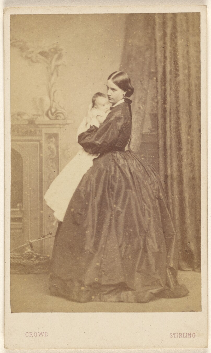 [Unidentified woman holding a child, standing]