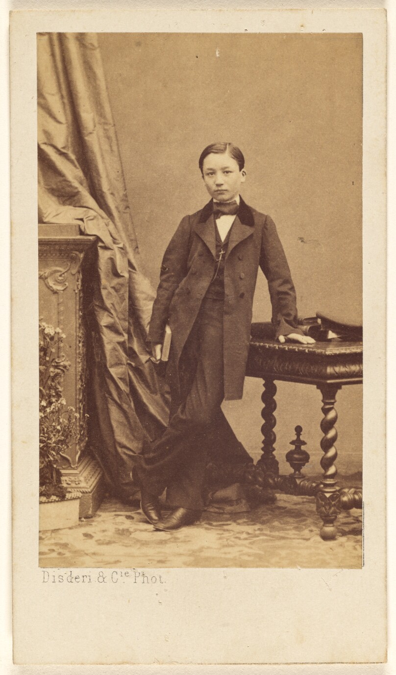[Unidentified little boy standing, holding a book]