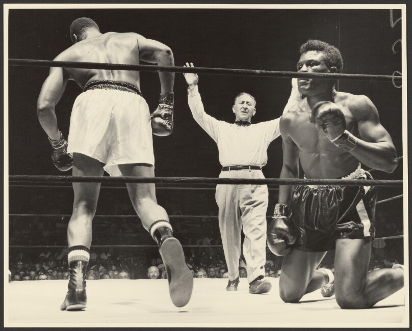 [Referee standing between boxers with arms raised]