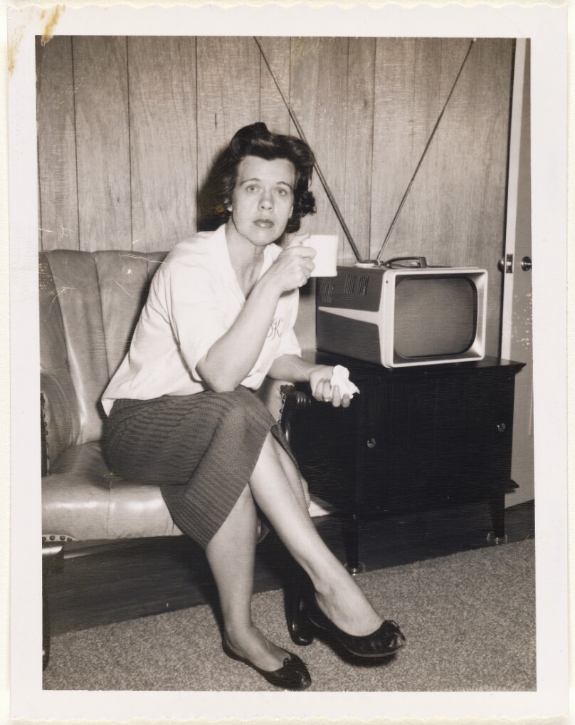 [Woman next to television with mug]