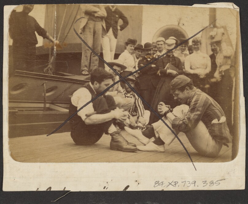 [Two men with hands bound on deck of ship]