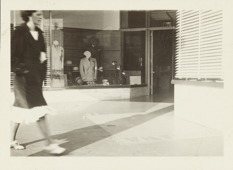 [Woman walking by store window]