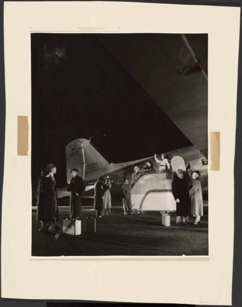 [Women being photographed boarding plane]
