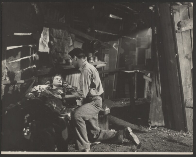 [Film still of man at a woman's bedside]