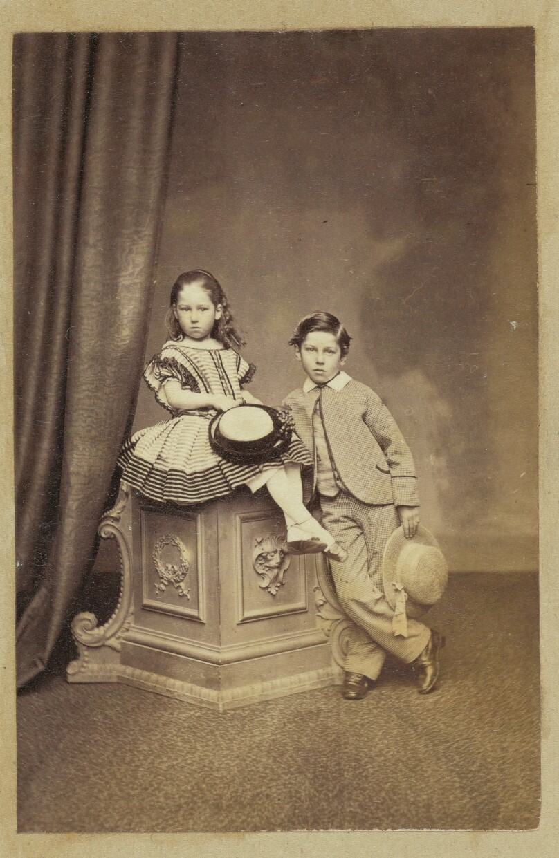 [Portrait of two children posing with pedestal]