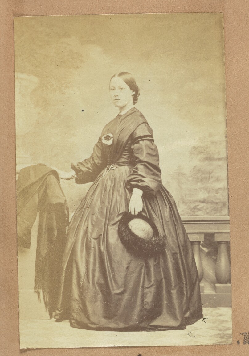 [Portrait of woman holding fur-trimmed hat]