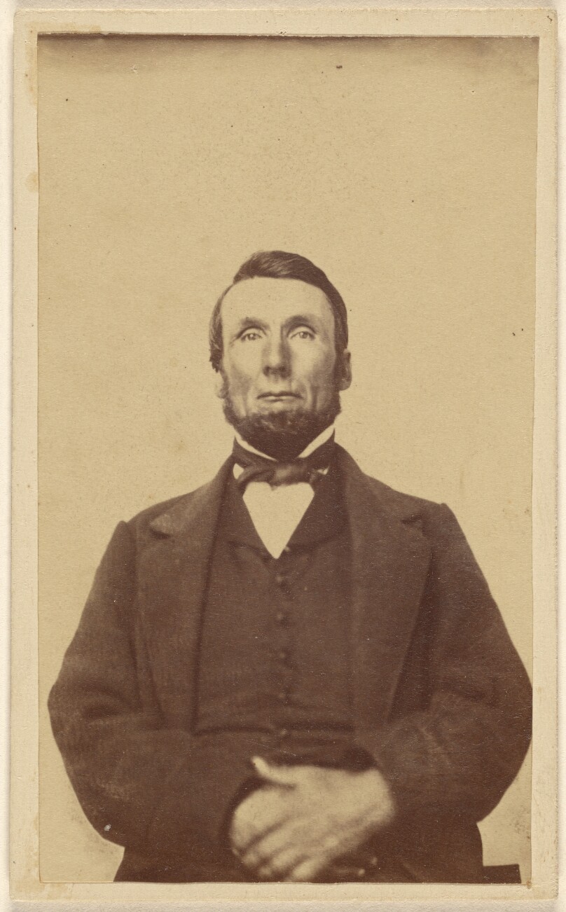 [Unidentified bearded man sans moustache, seated, with hands crossed]