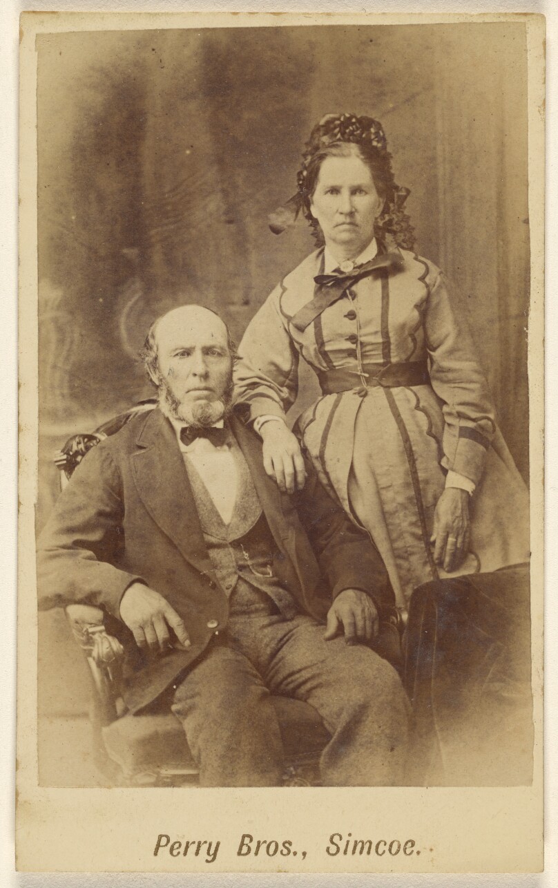 [Unidentified couple: bearded man, seated and woman, standing]