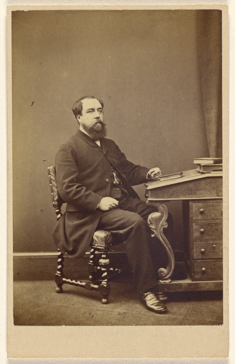 [Unidentified bearded man seated at writing desk, in 3/4 profile]