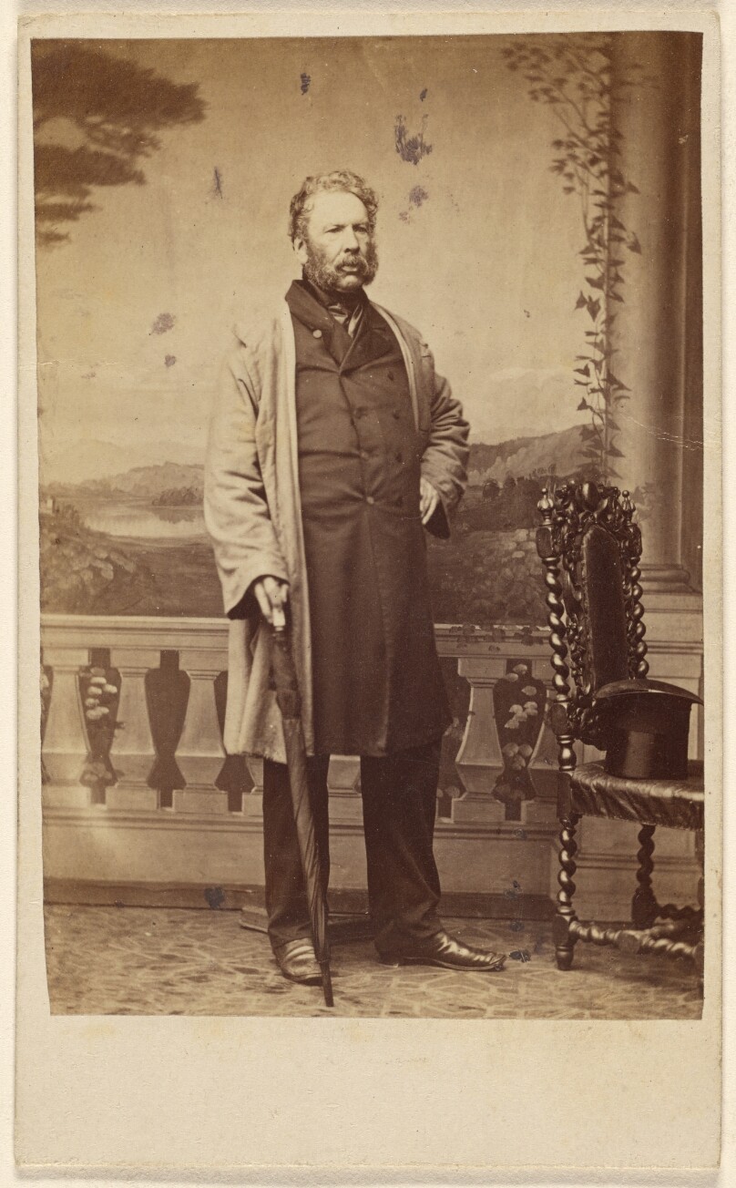 [Unidentified bearded man, holding an umbrella, standing]