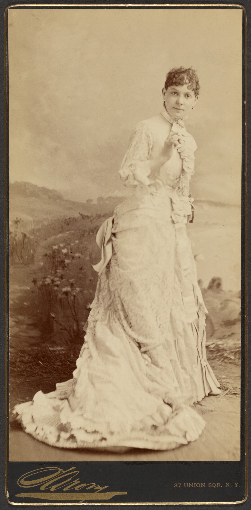 [Unidentified woman wearing a long, elegant white gown, standing]