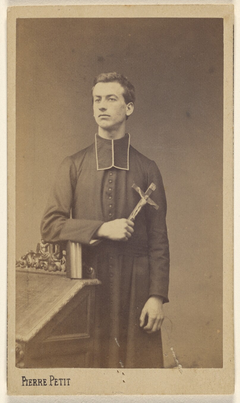 [Priest holding a crucifix, standing]